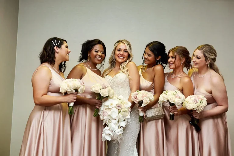Bride with five bridesmaids in blush gowns, laughing together
