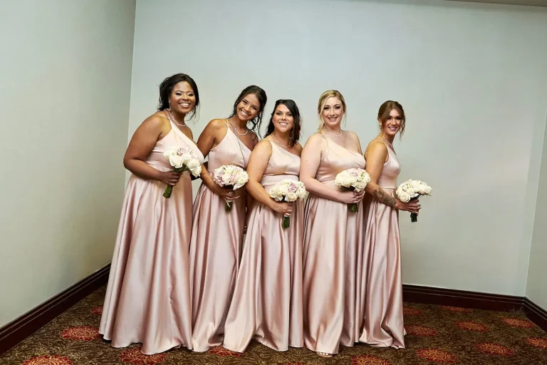 Five bridesmaids in blush gowns holding white bouquets