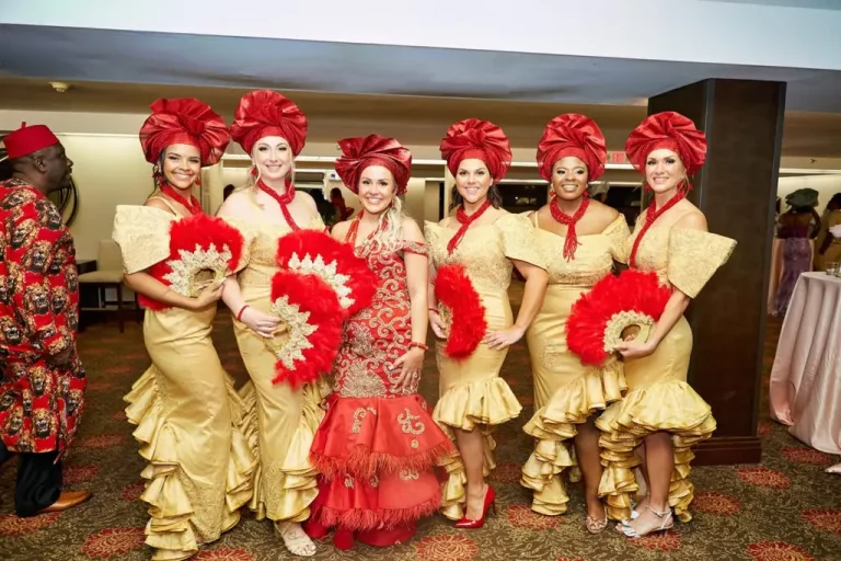 Bride in red with friends in gold gowns holding red feather fans