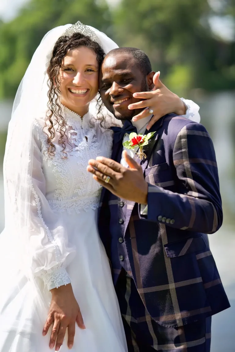 Bride and groom laughing together, the groom showing his new ring